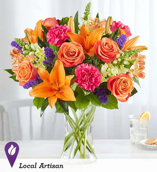Vibrant Floral Medley™ - LOCAL ARTISAN EXCLUSIVE Putting a bright start in somebody’s day starts with a beautiful gift. Our delightfully vibrant bouquet is filled with a medley of blooms in cheerful pops of orange, pink and yellow, with plenty of lush greenery mixed in. Designed by the talented Breanna Cartwright from Fresh Ideas Flowers Company in Modesto, California, it’s the perfect pick-me-up surprise, whatever the sentiment.  All-around arrangement with orange roses, Asiatic lilies and Peruvian lilies (alstroemeria), hot pink carnations, yellow snapdragons and purple statice; accented with assorted greenery Artistically designed in a clear glass vase; measures 8"H Large arrangement measures approximately 22"H x 14"W Medium arrangement measures approximately 21"H x 13"W Small arrangement measures approximately 20"H x 12"W Our florists select the freshest flowers available, so colors, varieties and container may vary due to local availability To ensure lasting beauty, Asiatic and Peruvian lilies may arrive in bud form and will fully bloom over the next few days