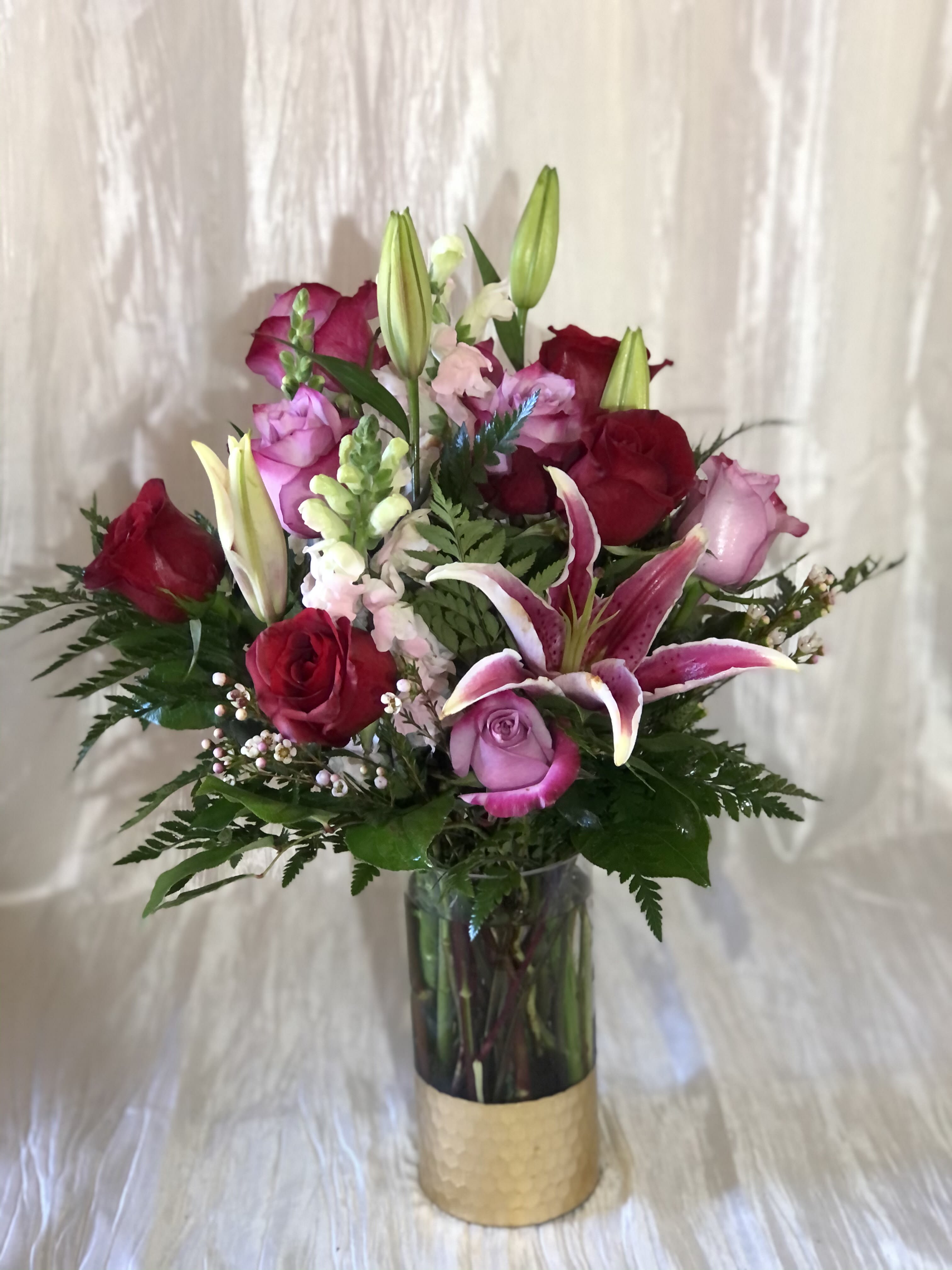Bouquet of red and pink roses with lilies in a glass vase