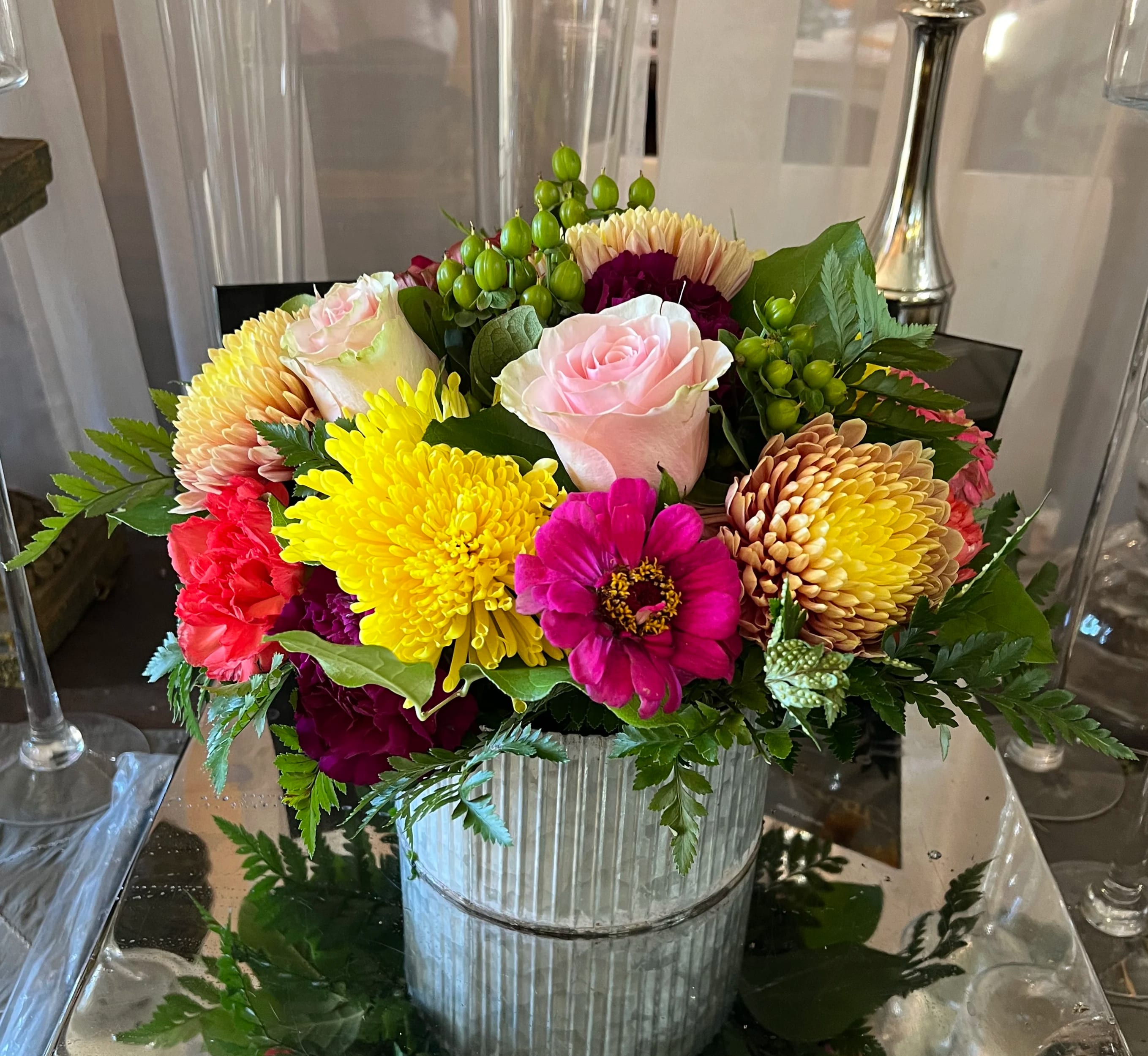 Mixed bouquet of roses, chrysanthemums, and zinnias in a ribbed metal container