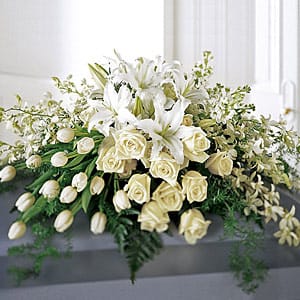 White lilies and roses arranged in a low casket spray