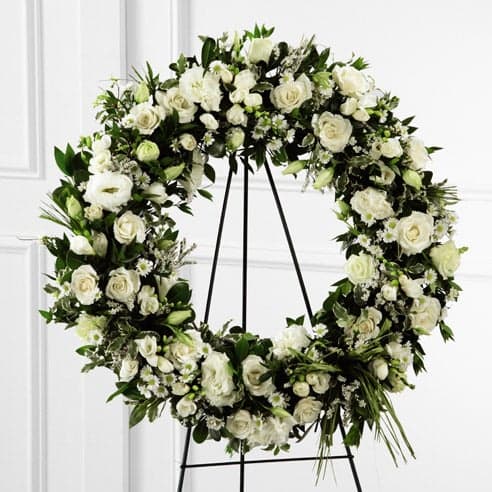 Large white floral wreath on a black stand