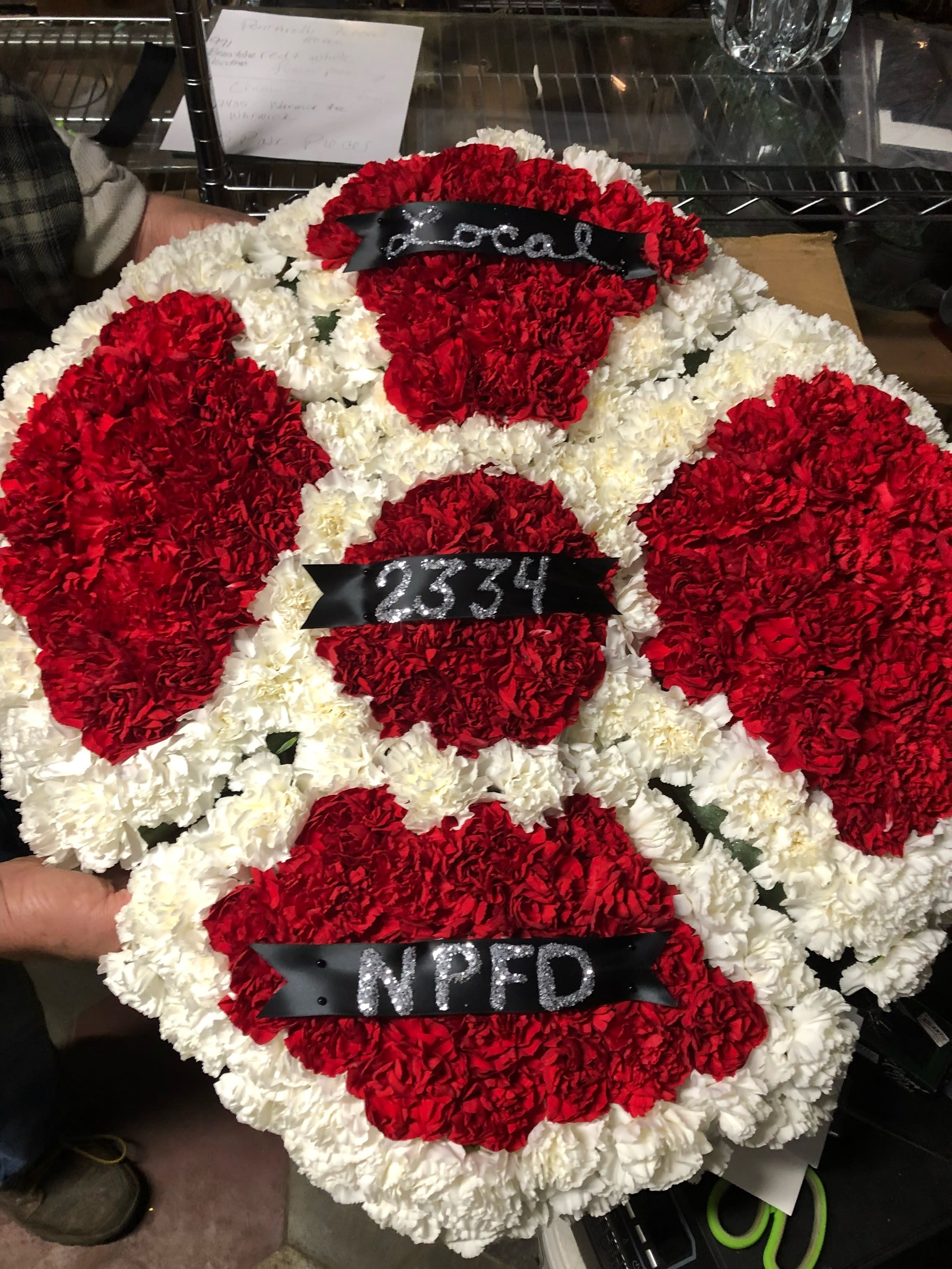 Red and white carnation wreath with black ribbons and silver lettering