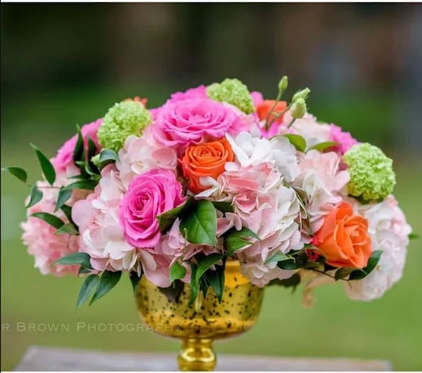 Pink and orange roses with pale hydrangeas in a gold vase