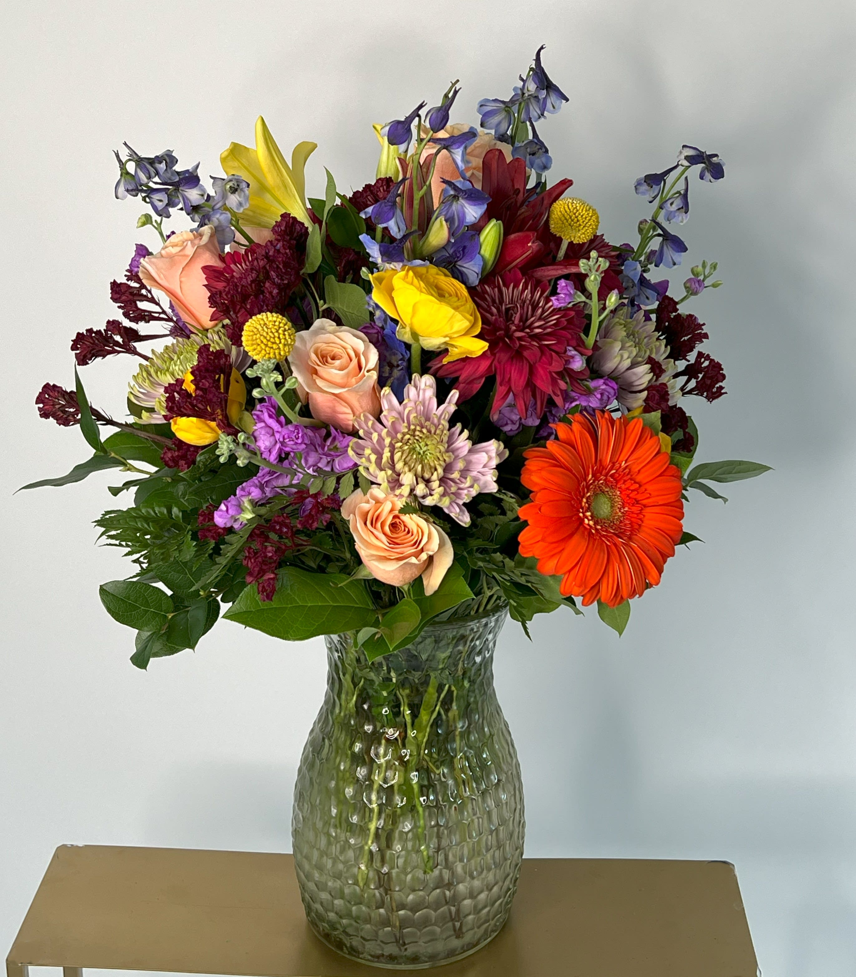 Mixed bouquet in a textured glass vase with orange gerbera daisies and roses