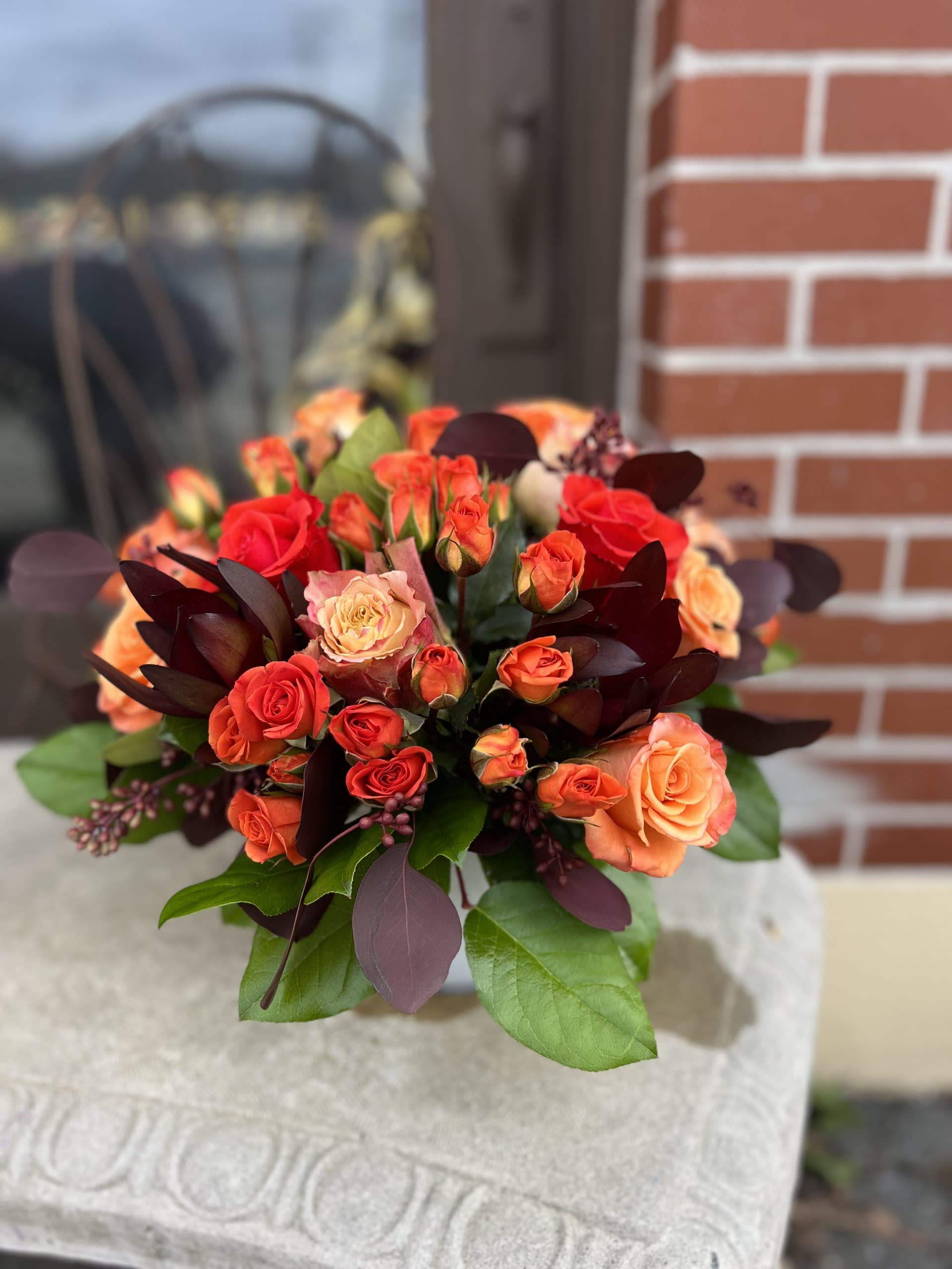 Bouquet of orange and red roses with dark foliage