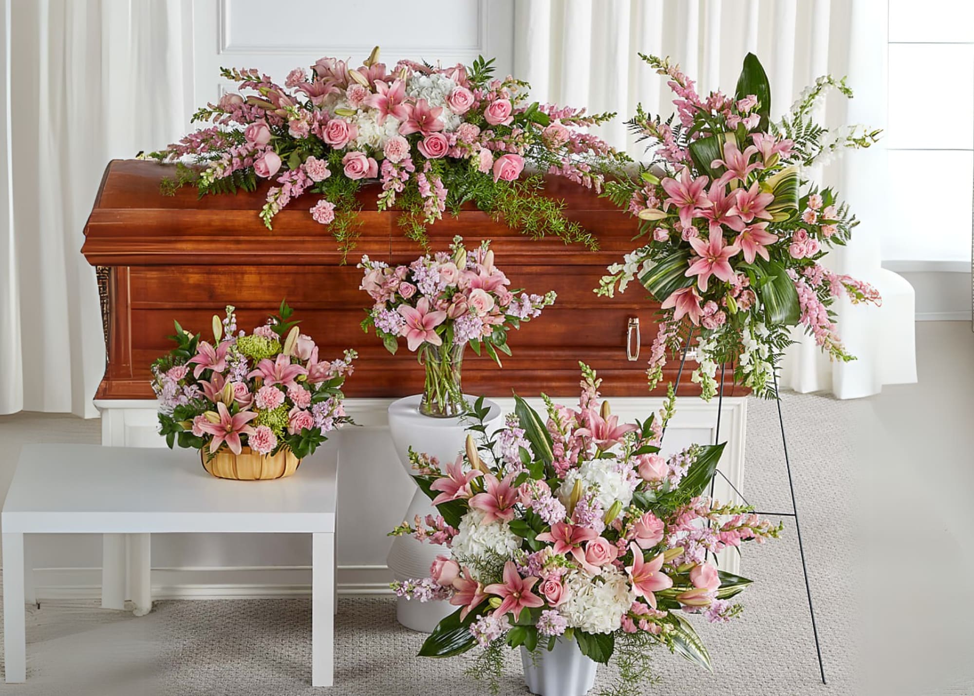 Pink and white funeral flowers arranged around a casket