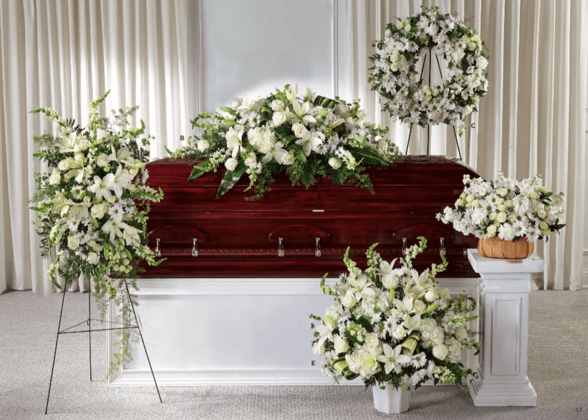 White floral funeral arrangements around a casket