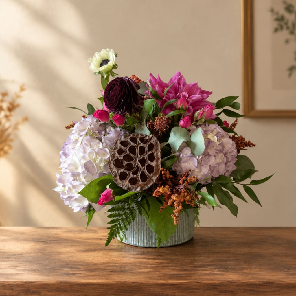 Mixed bouquet in a ribbed metal vase with hydrangeas and bright pink blooms