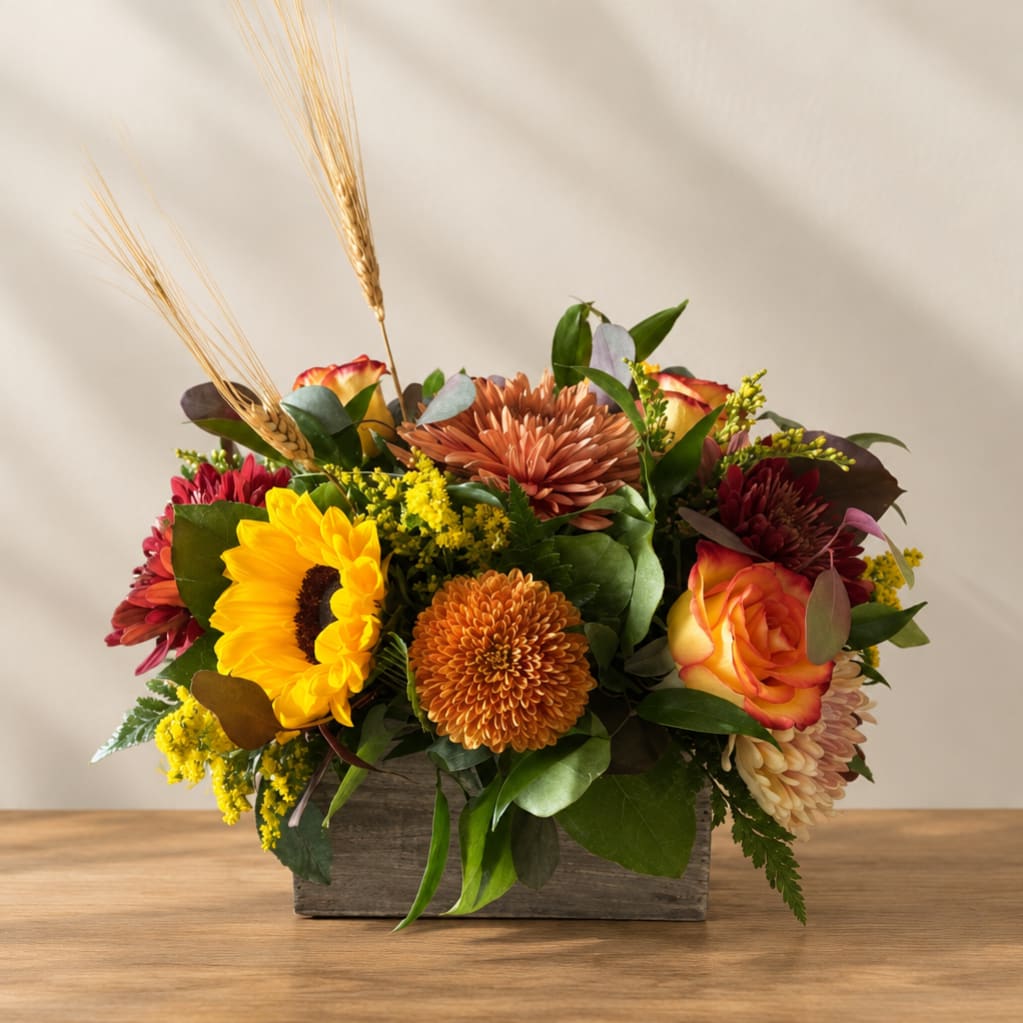 Mixed autumn bouquet in a wooden box with sunflowers and chrysanthemums