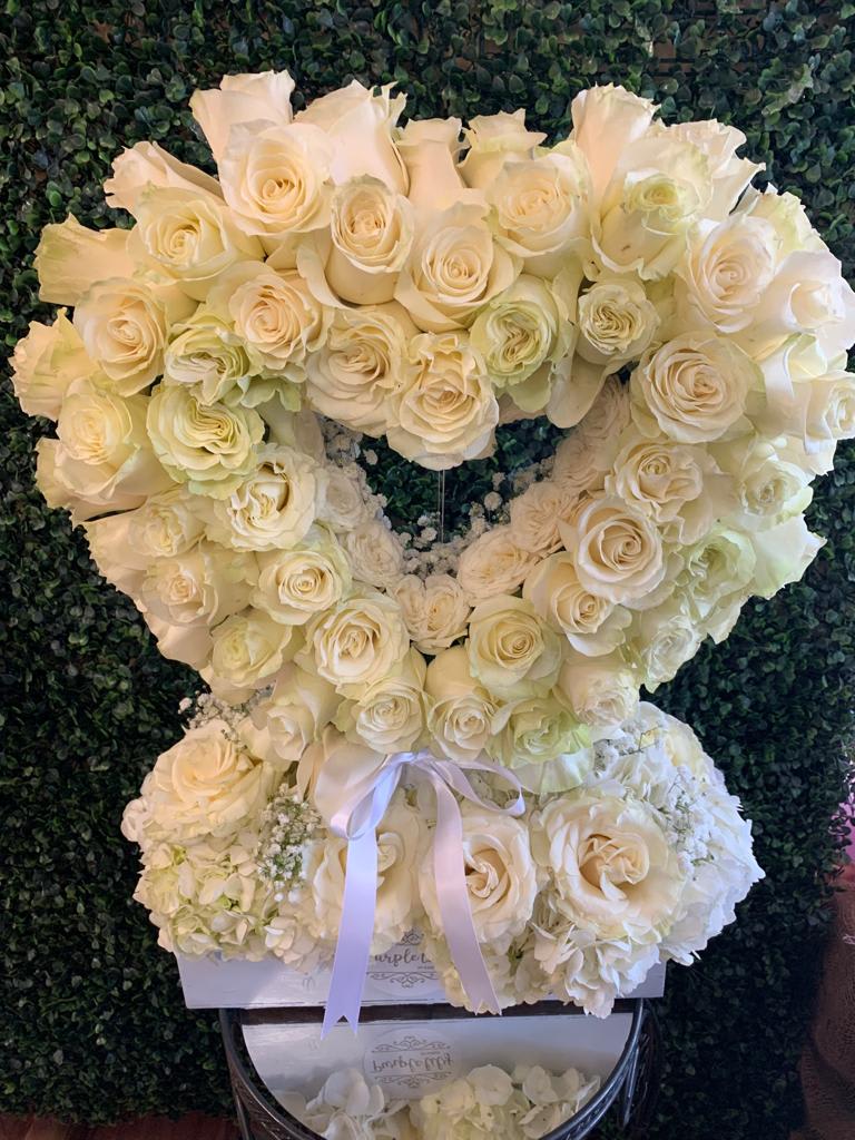 Heart-shaped arrangement of white roses with a ribbon bow