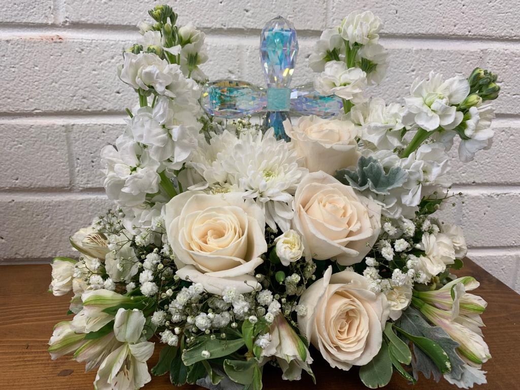 White floral arrangement with cream roses and a crystal cross topper