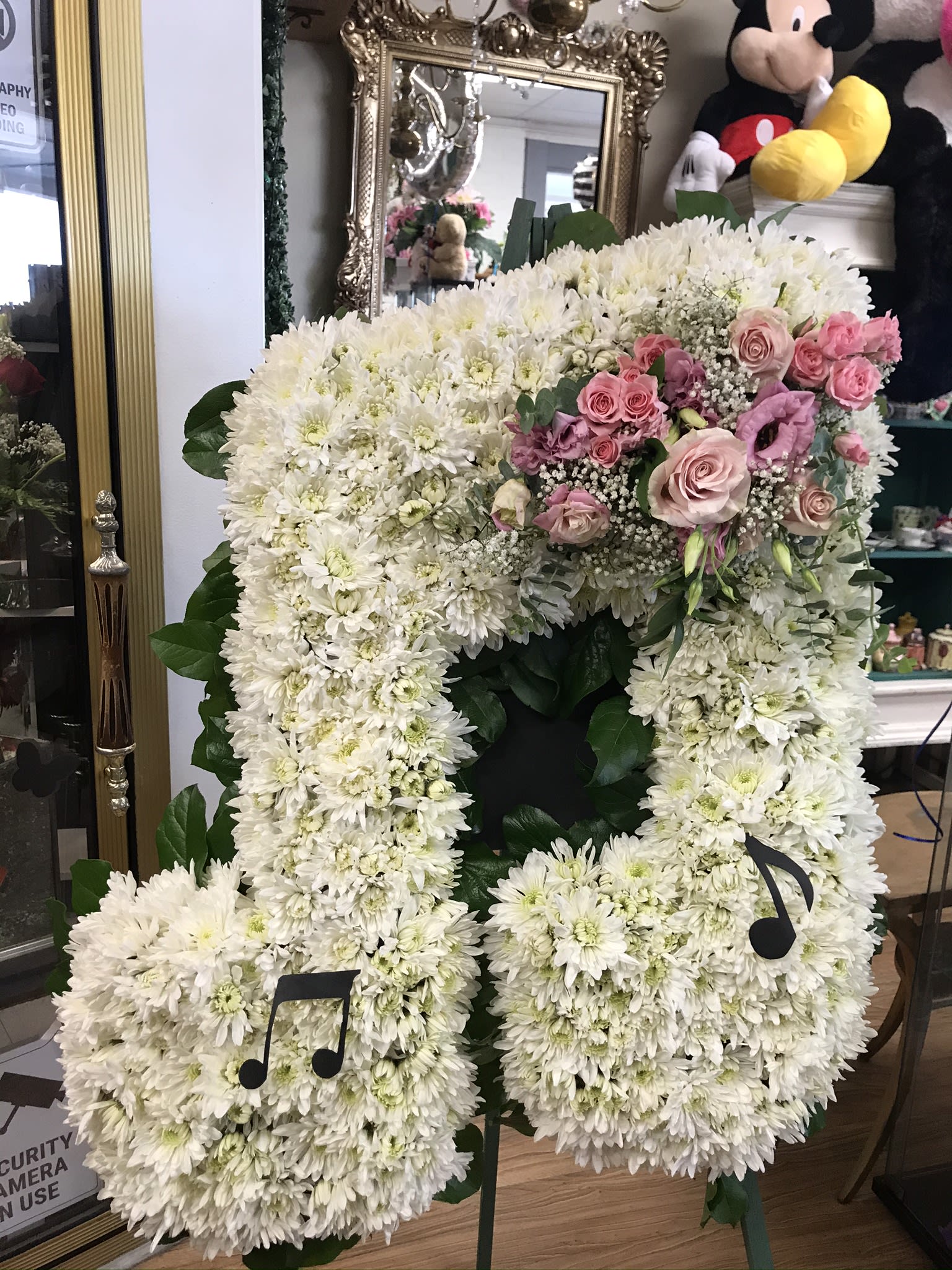 Large white floral standing arrangement with pink roses and music note accents