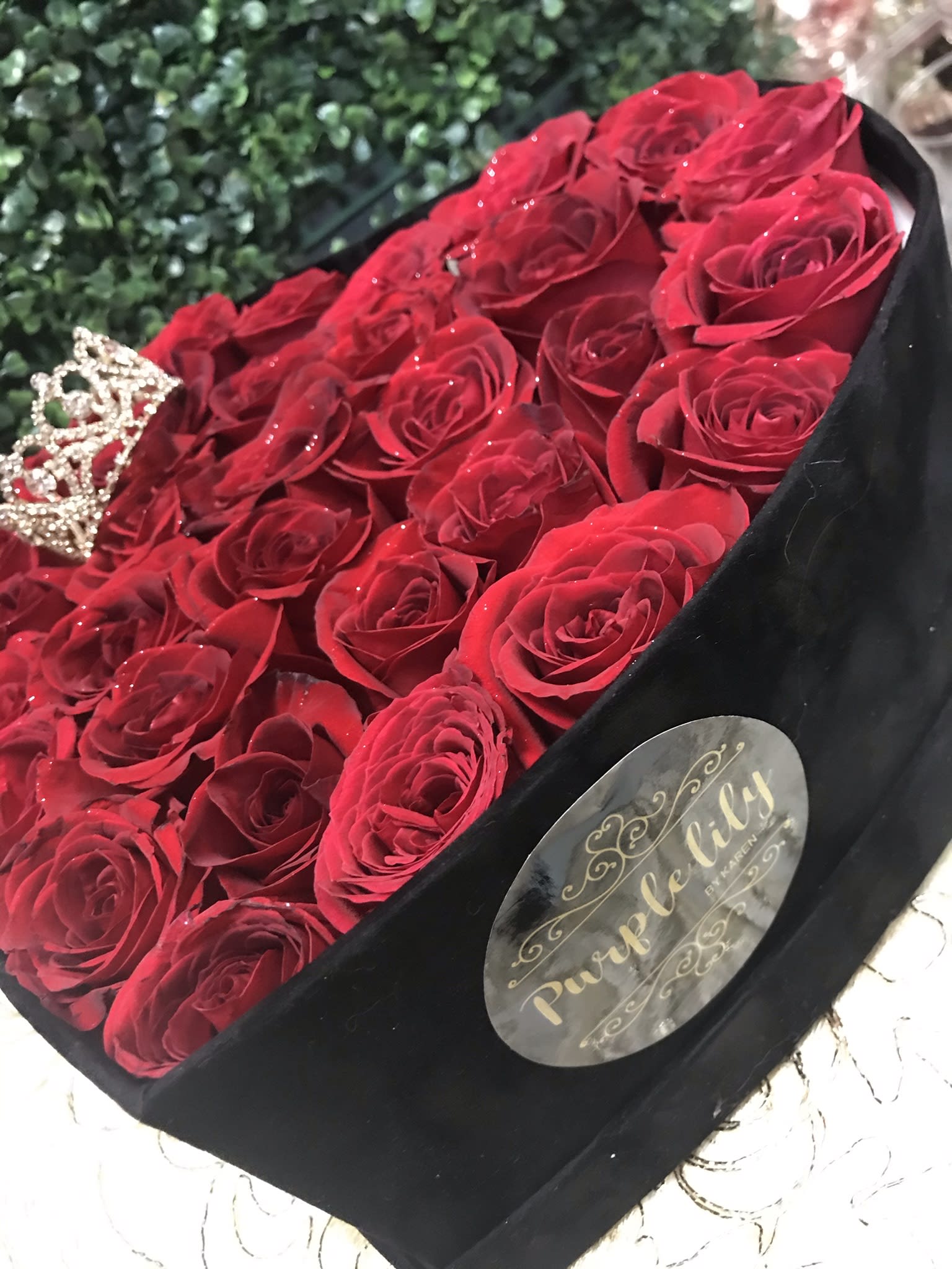 Bouquet of red roses in a black box with a small crown decoration