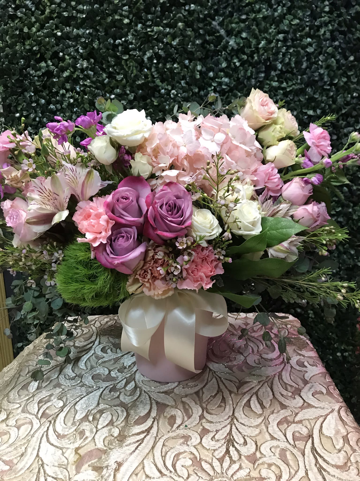 Pink and purple mixed flower arrangement in a ribbon-tied vase