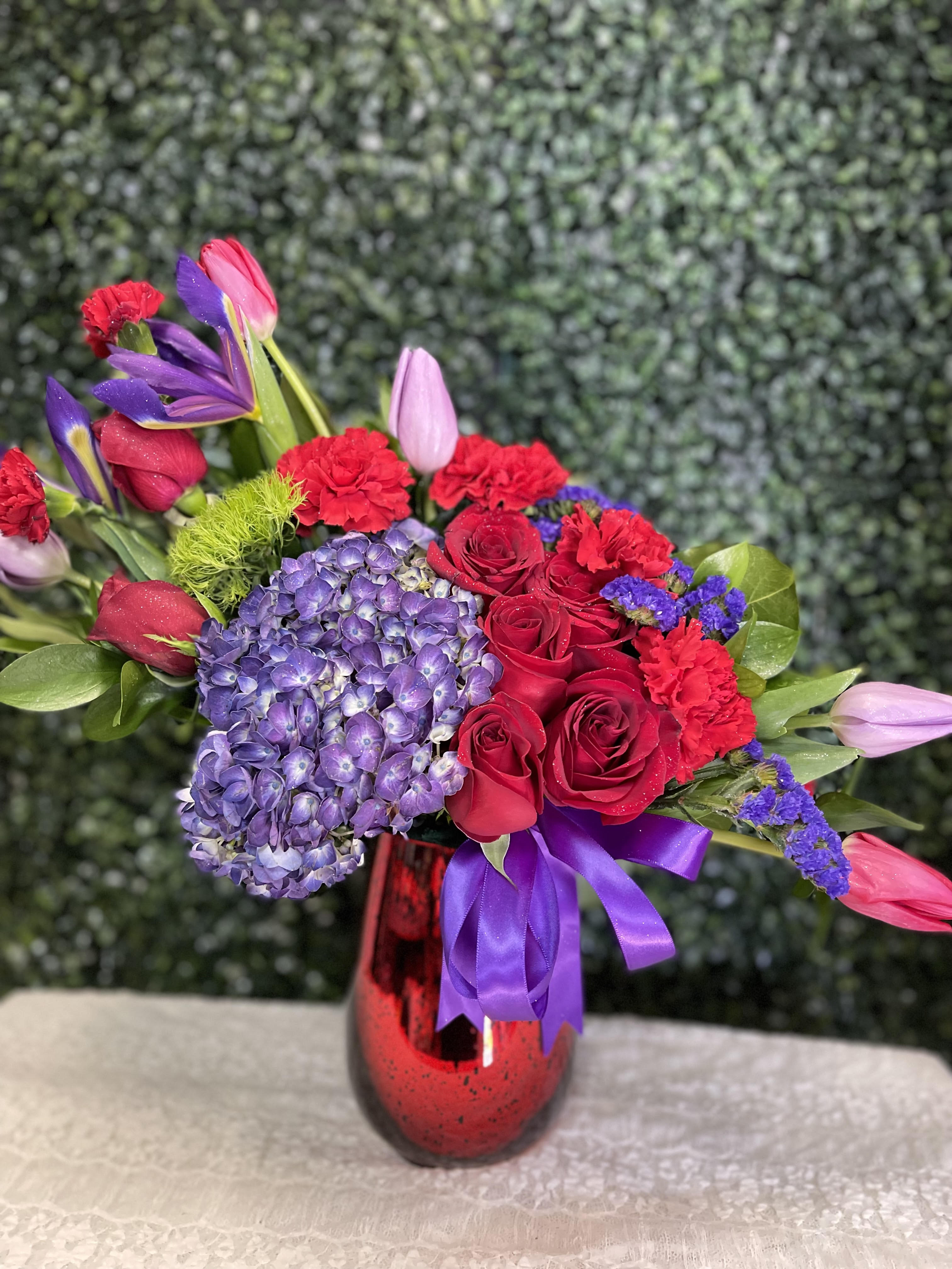 Bouquet of red roses, purple hydrangea, and tulips in a red vase