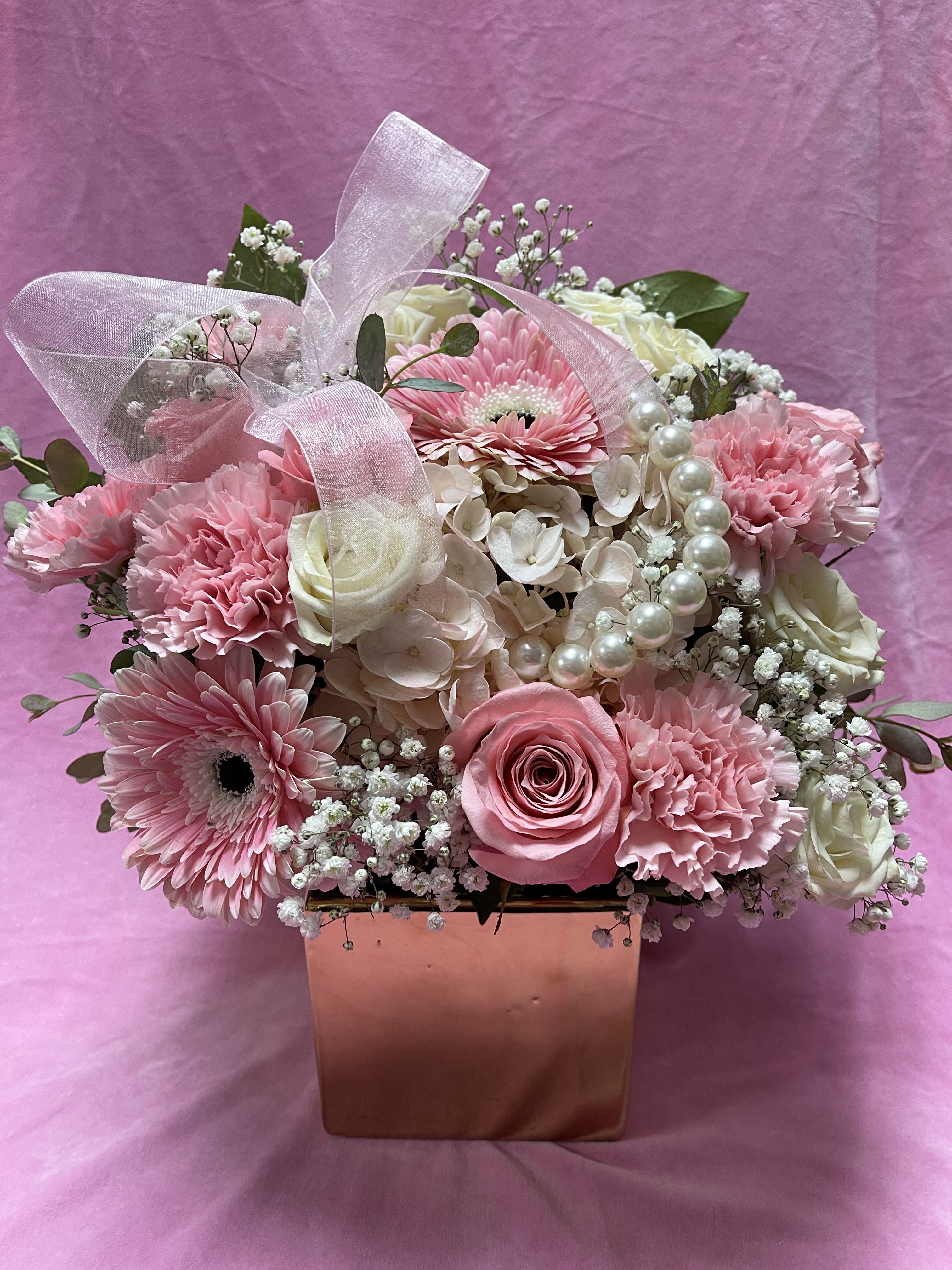 Pink and white flower arrangement in a square box with a sheer ribbon