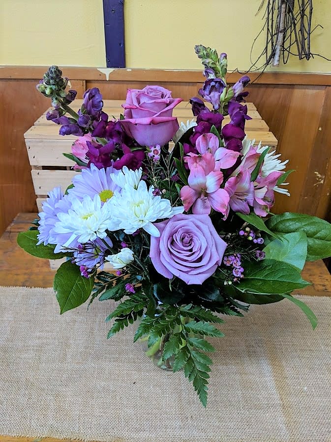 Lavender roses with white daisies and pink-purple blooms in a vase