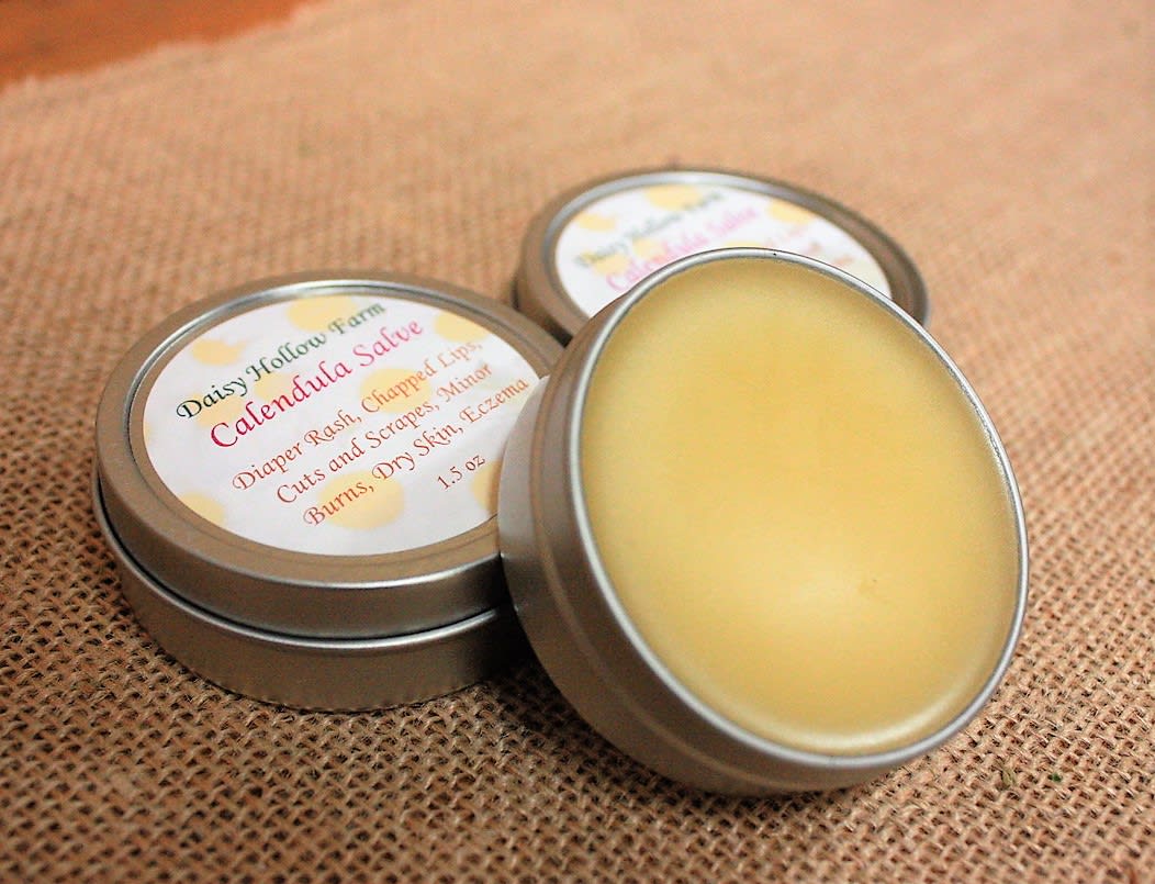 Three tins of calendula salve on burlap fabric