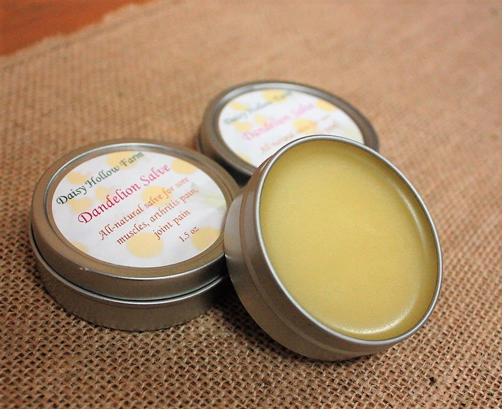 Three tins of yellow salve on burlap fabric
