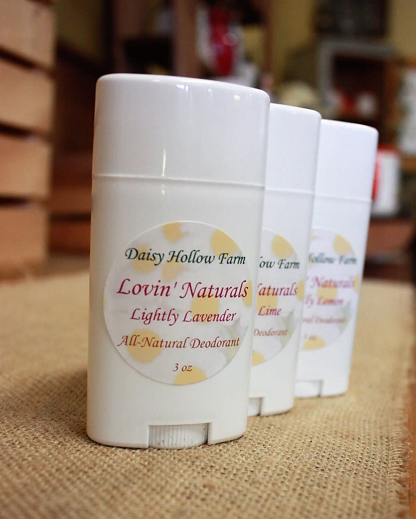 Three white deodorant sticks with lavender labels on a burlap surface