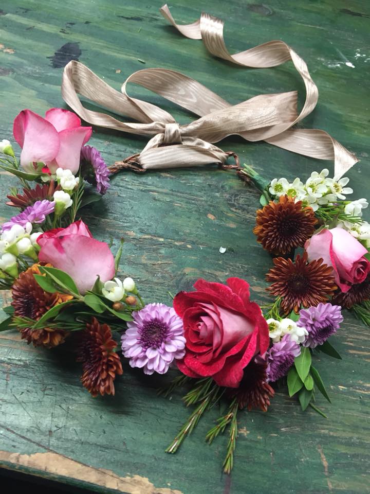 Floral wreath with pink roses and purple daisies on a ribbon tie