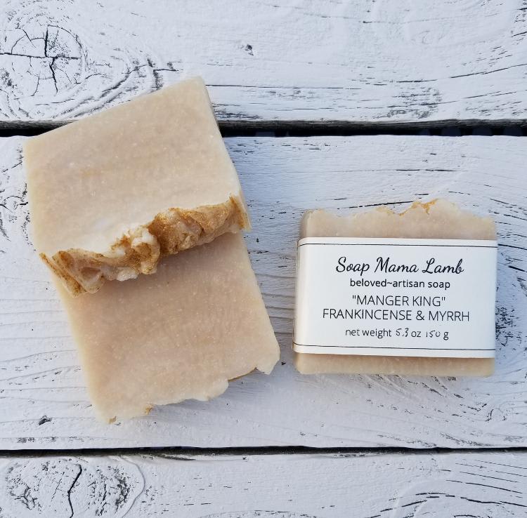 Two bars of beige artisan soap on a white wooden surface