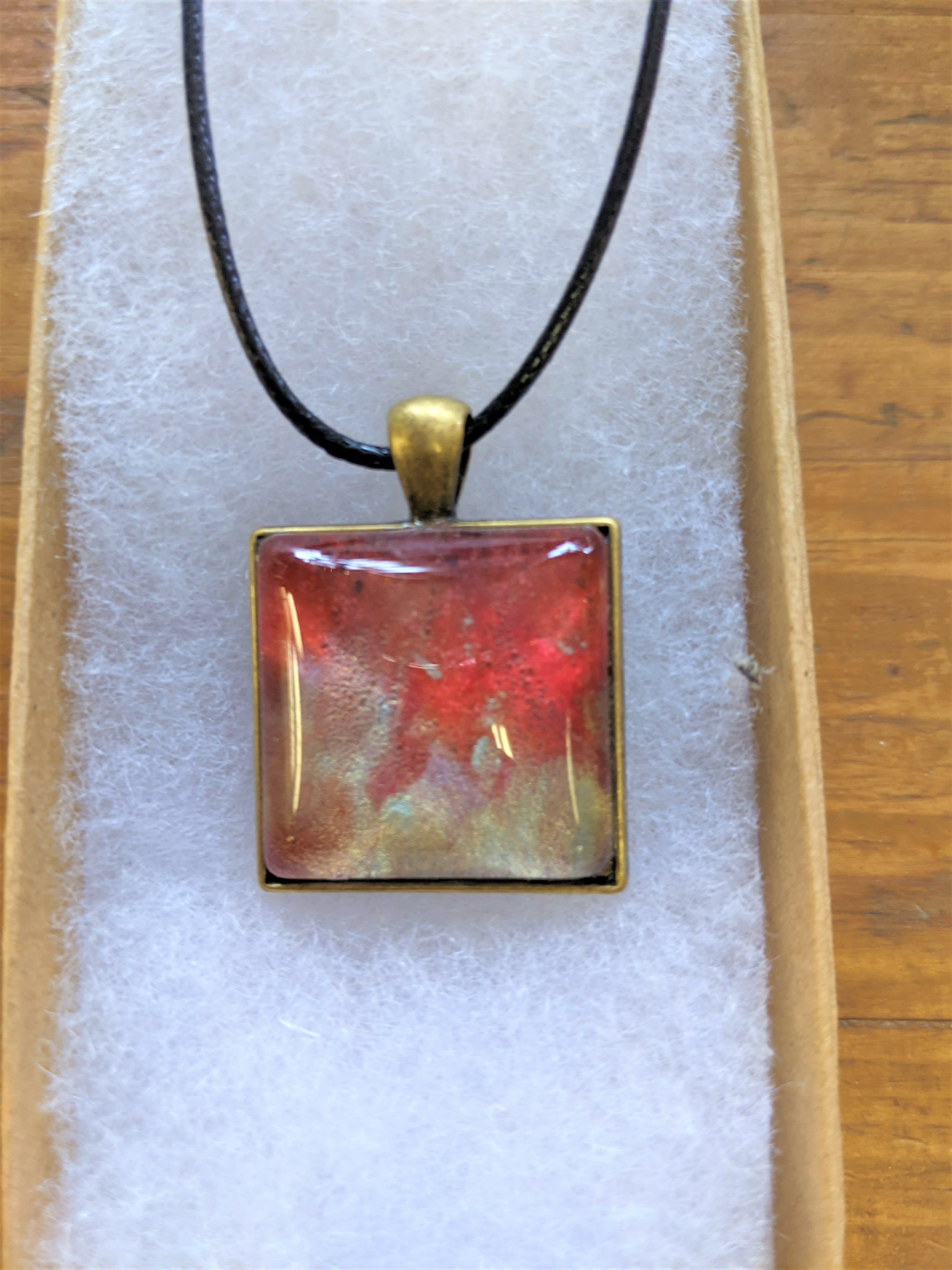 Square red pendant necklace on a black cord in a gift box