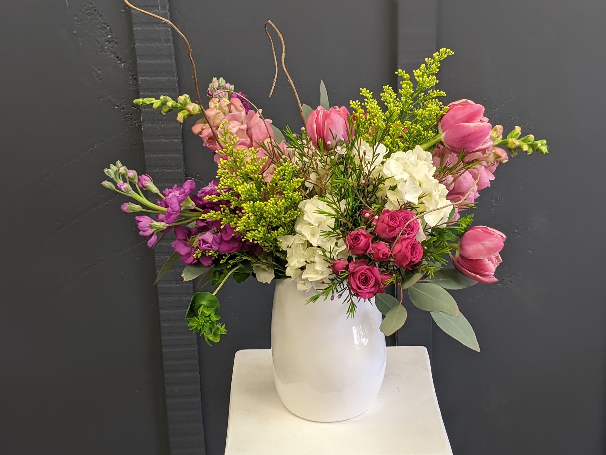 Mixed pink and white floral arrangement in a white vase