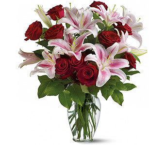 Bouquet of red roses and pink lilies in a clear glass vase