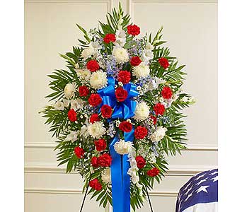 Standing floral spray with red and white flowers and a blue ribbon