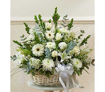 White floral arrangement in a wicker basket with a silver ribbon
