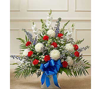 Red and white floral spray with a blue ribbon in a vase