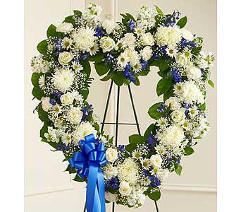 Heart-shaped floral wreath with white and blue flowers on a stand