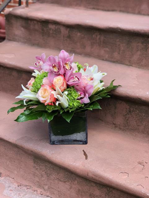 Pink and white floral arrangement in a square glass vase