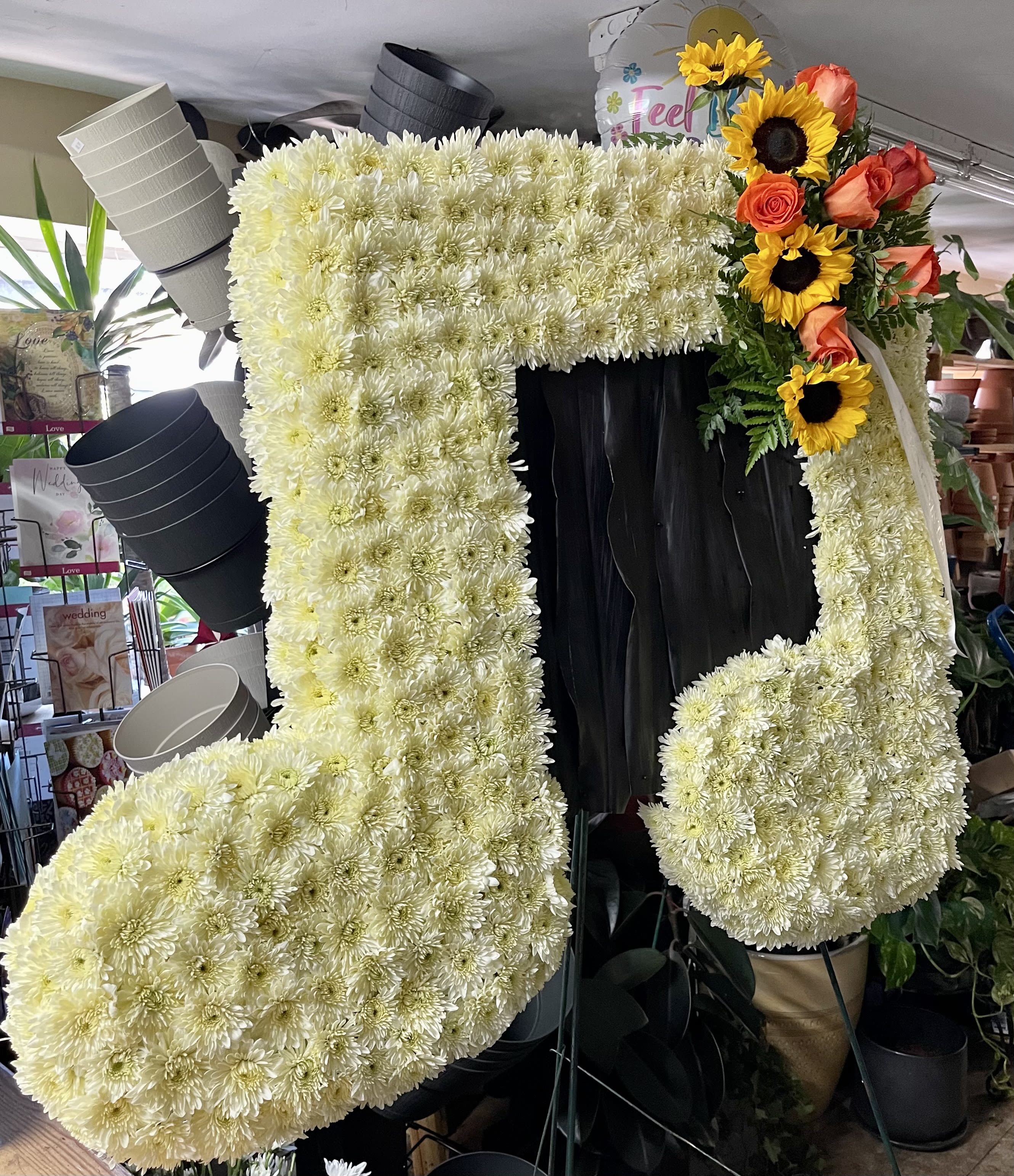 Large floral number-shaped display made of white chrysanthemums with sunflowers and roses