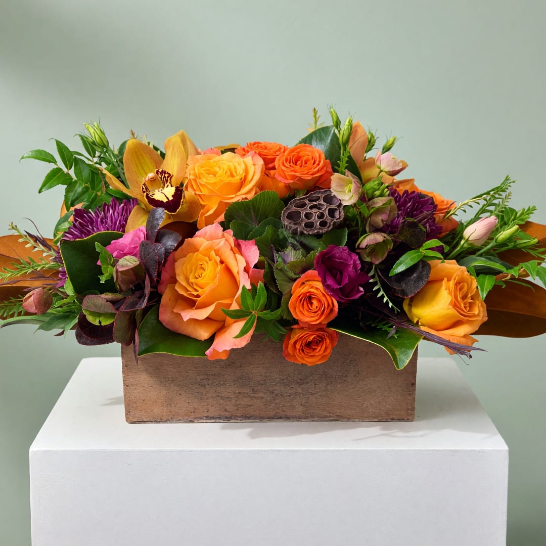 Orange and purple floral arrangement in a wooden box
