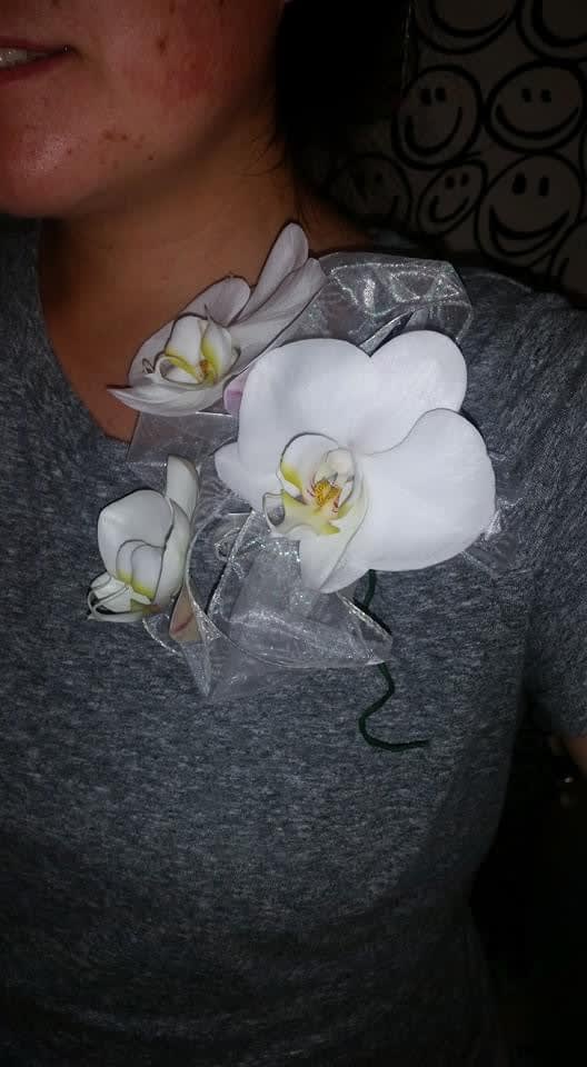 White orchid corsage with sheer ribbon on a person's shoulder