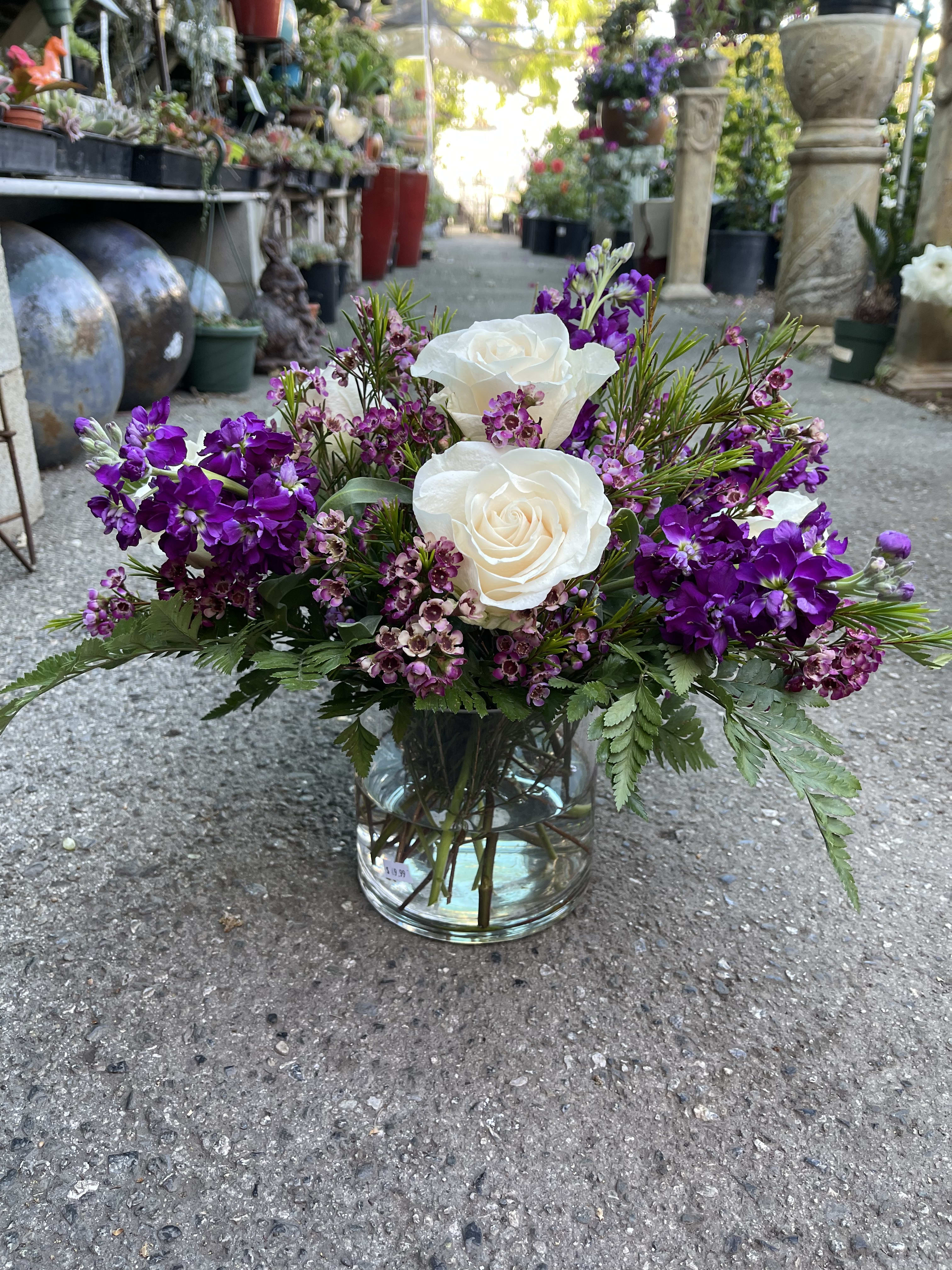 White roses and purple flowers arranged in a glass vase