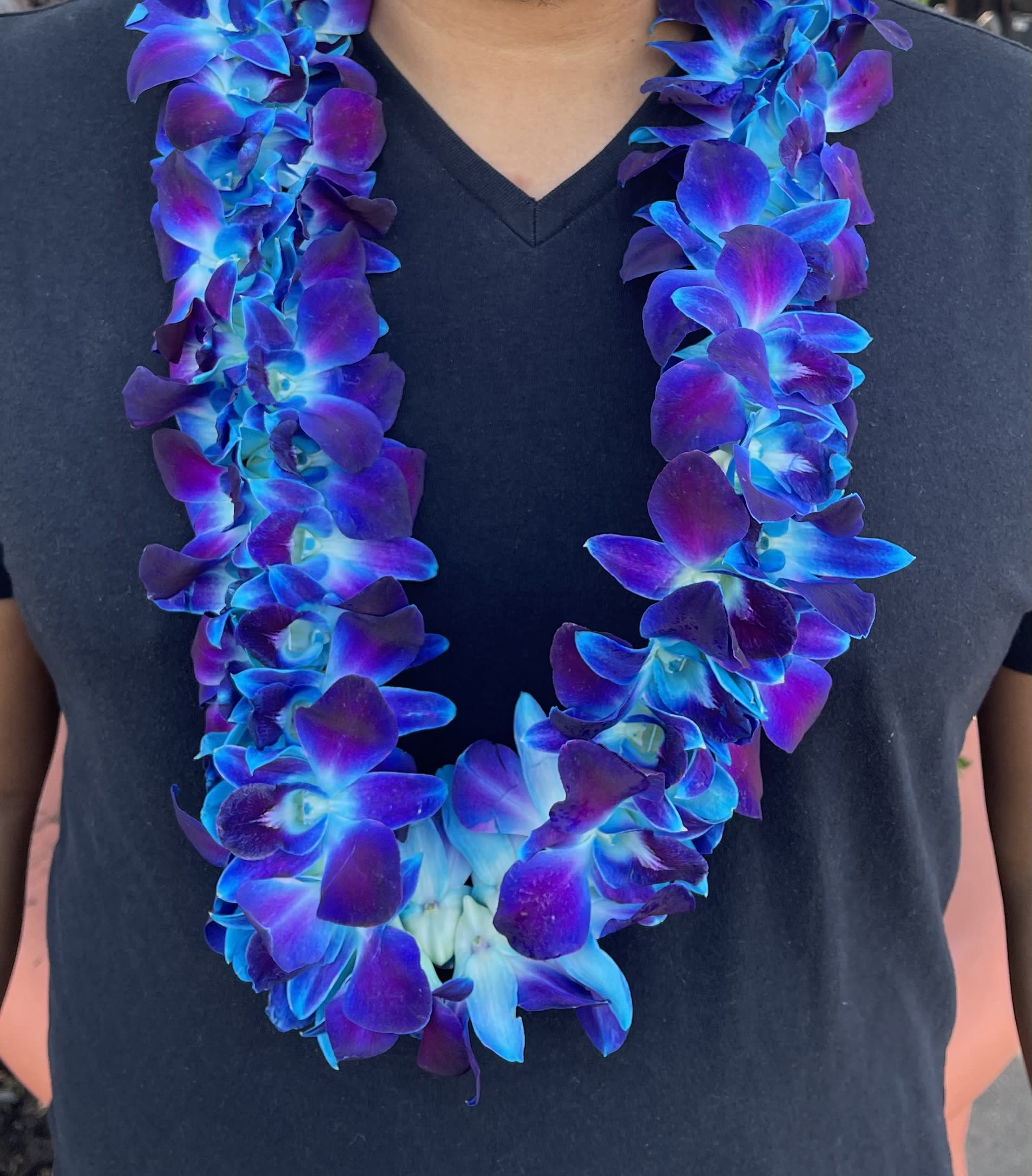 Blue and purple orchid lei worn around a black shirt