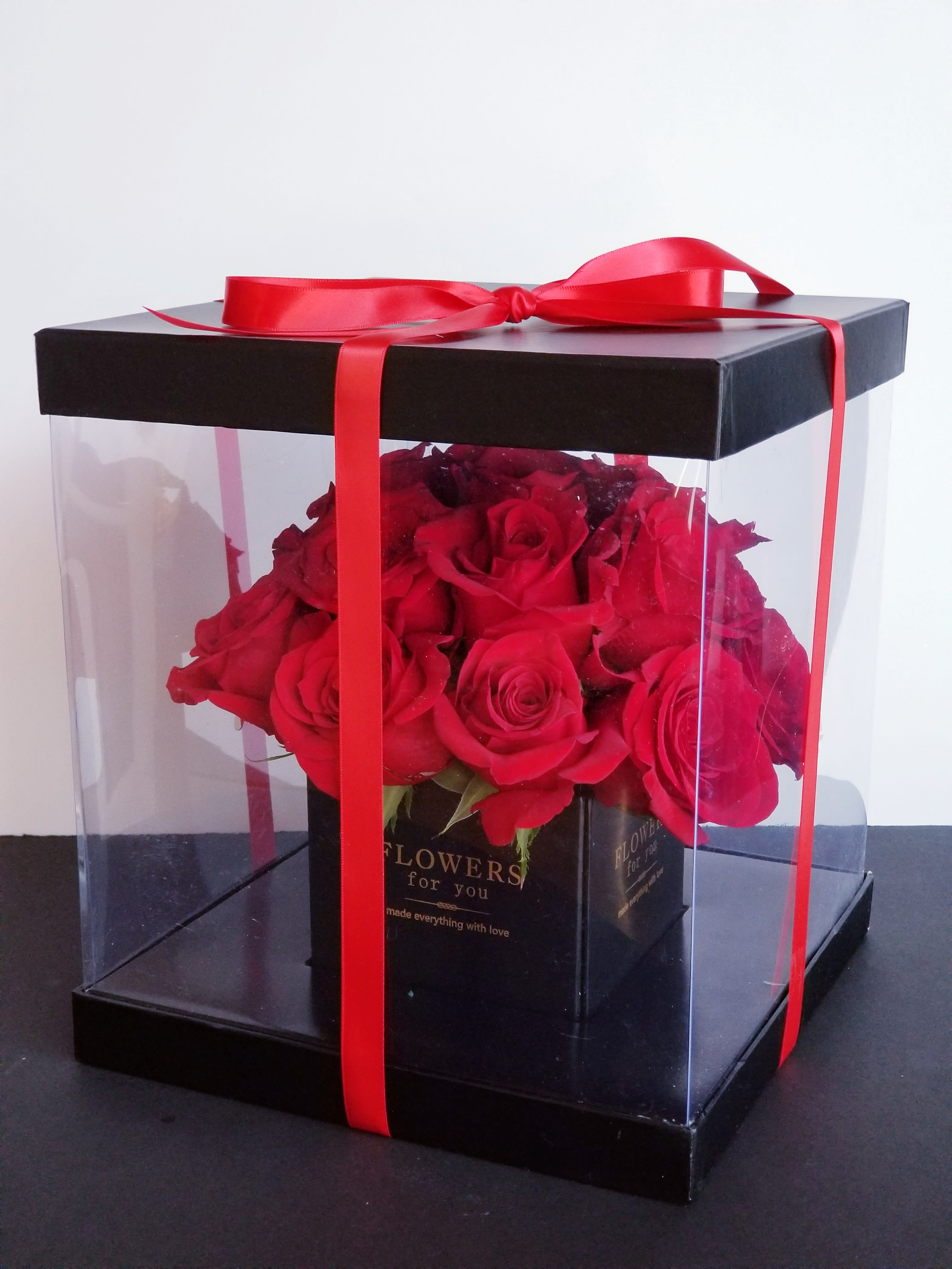 Red roses in a clear gift box tied with a red ribbon