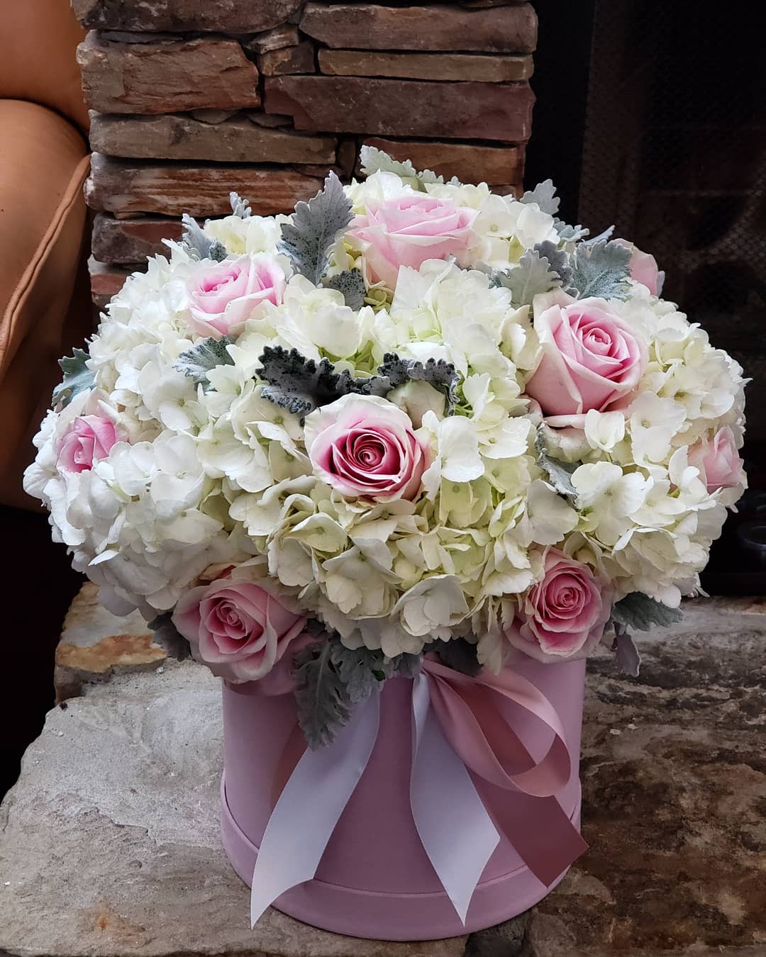 Pink roses and white hydrangeas in a pink hatbox with ribbon