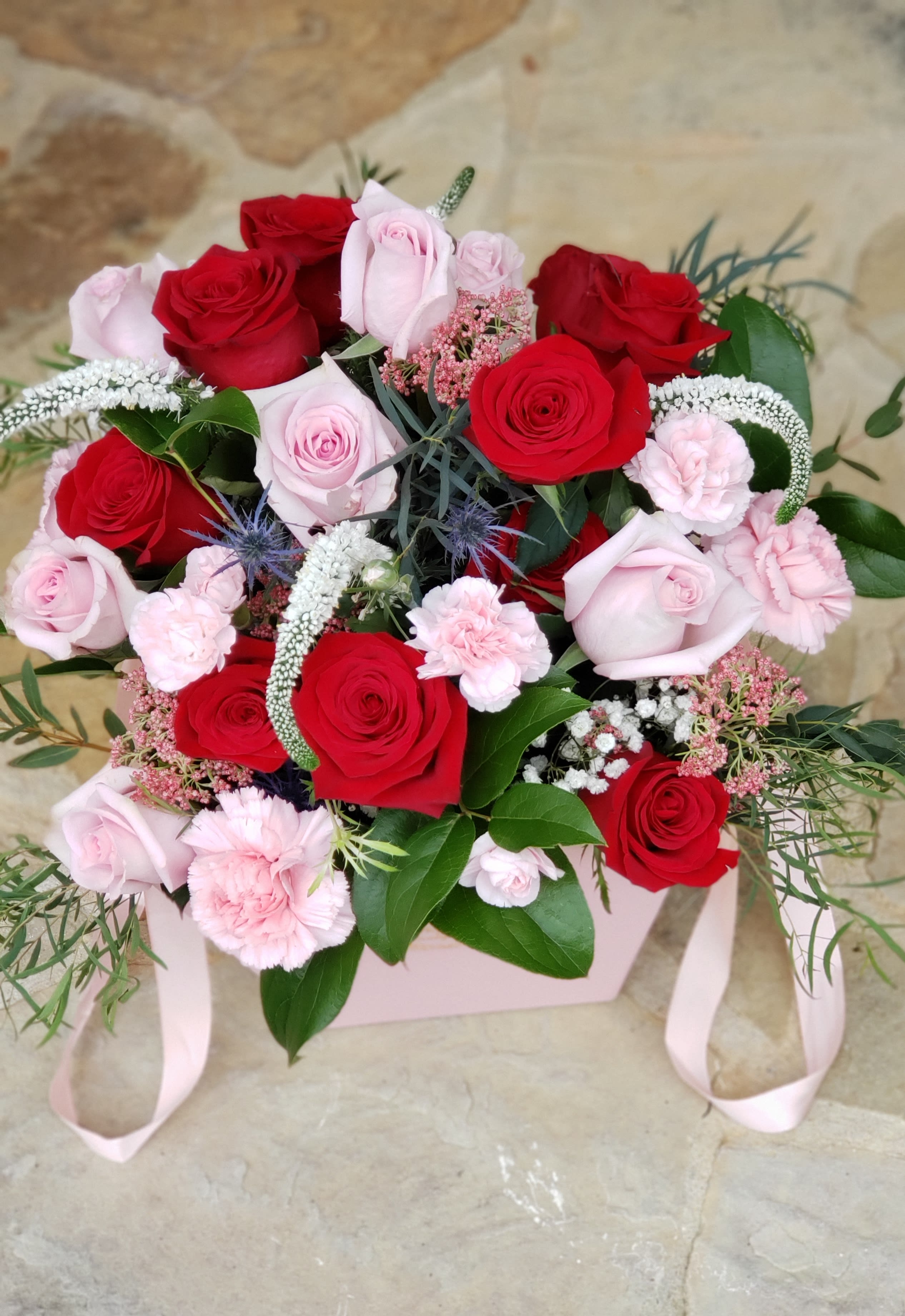 Bouquet of red and pale pink roses with pink carnations in a pink box