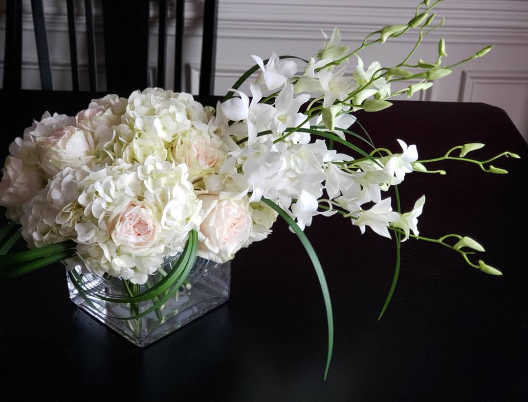 White and pale pink floral arrangement in a square glass vase