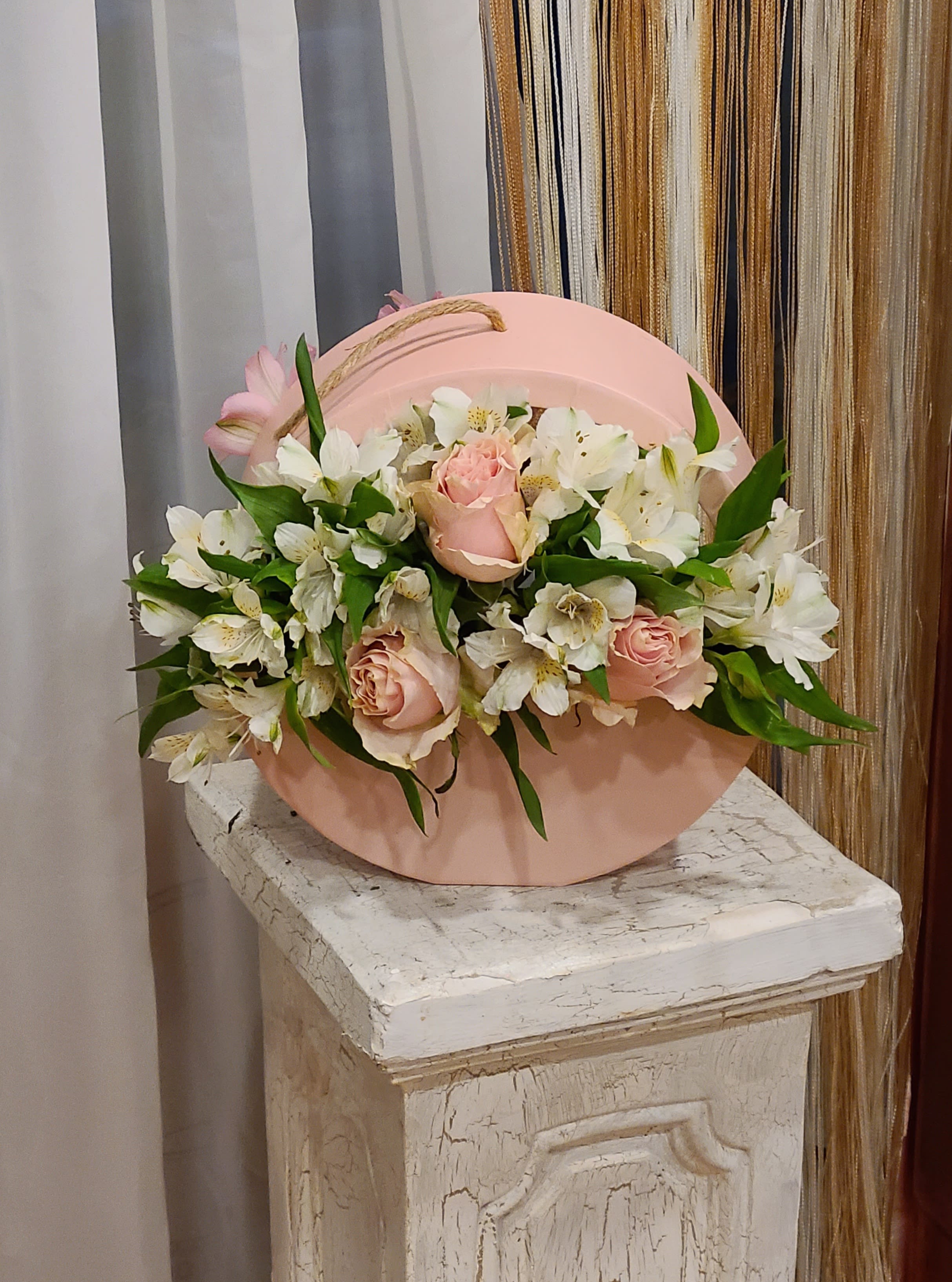 Pink roses and white lilies arranged in a round pink box