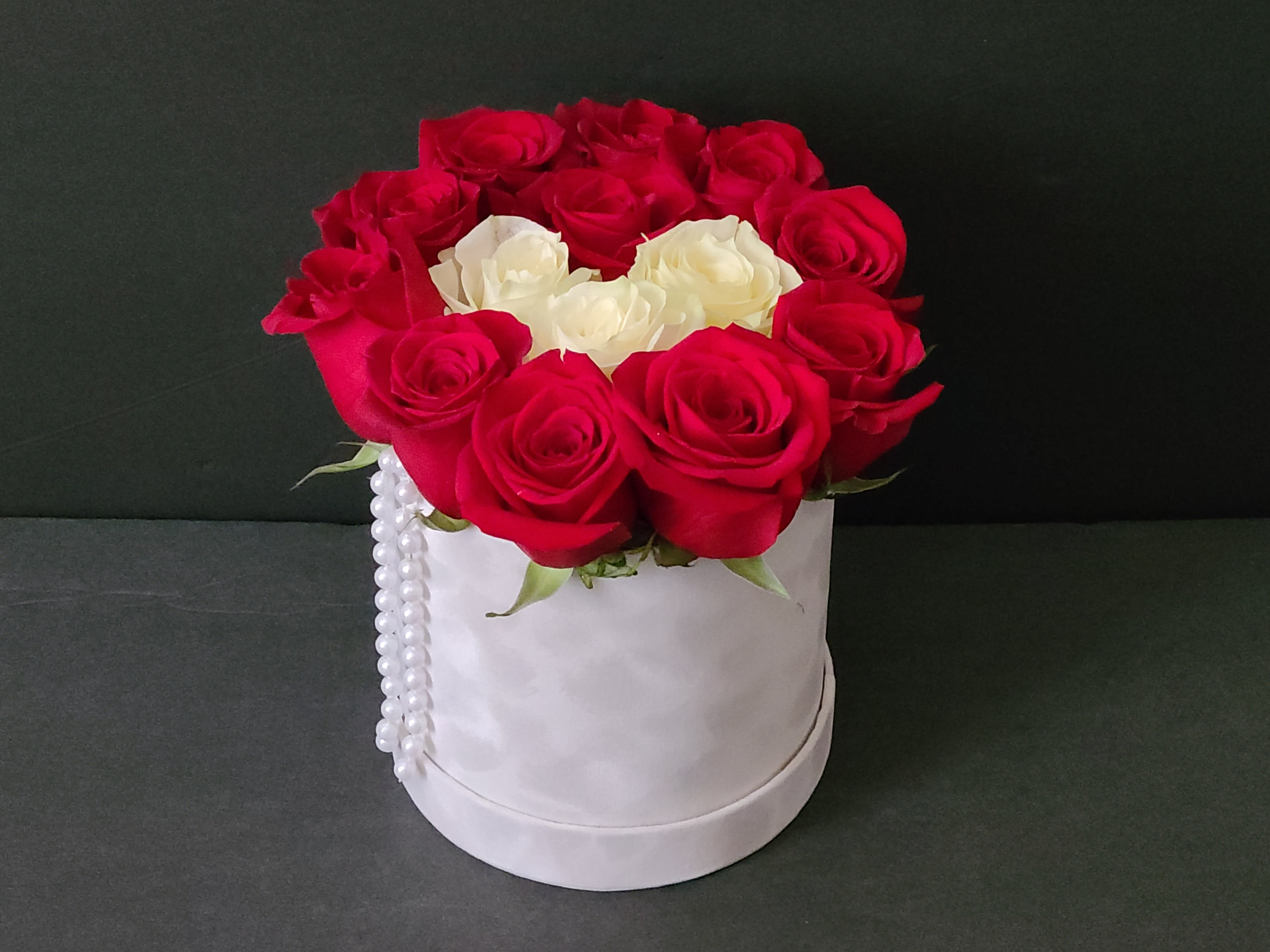 Red and white roses arranged in a white hat box with pearl trim