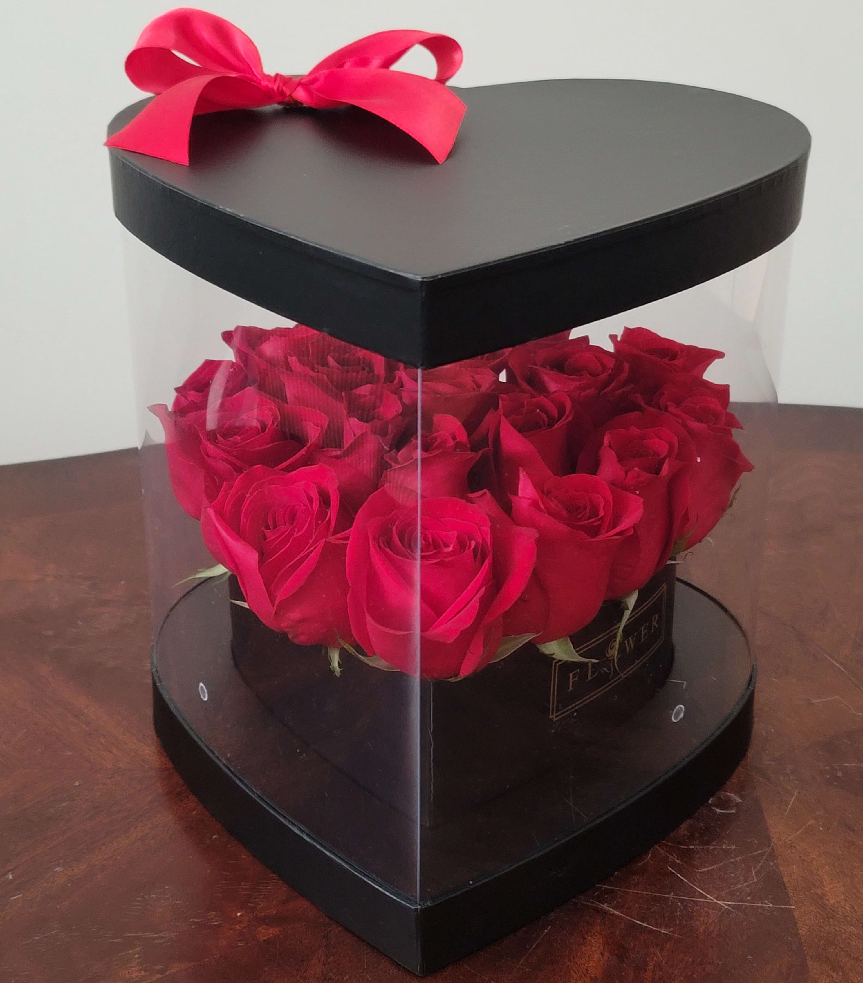 Heart-shaped box of red roses with a pink ribbon bow