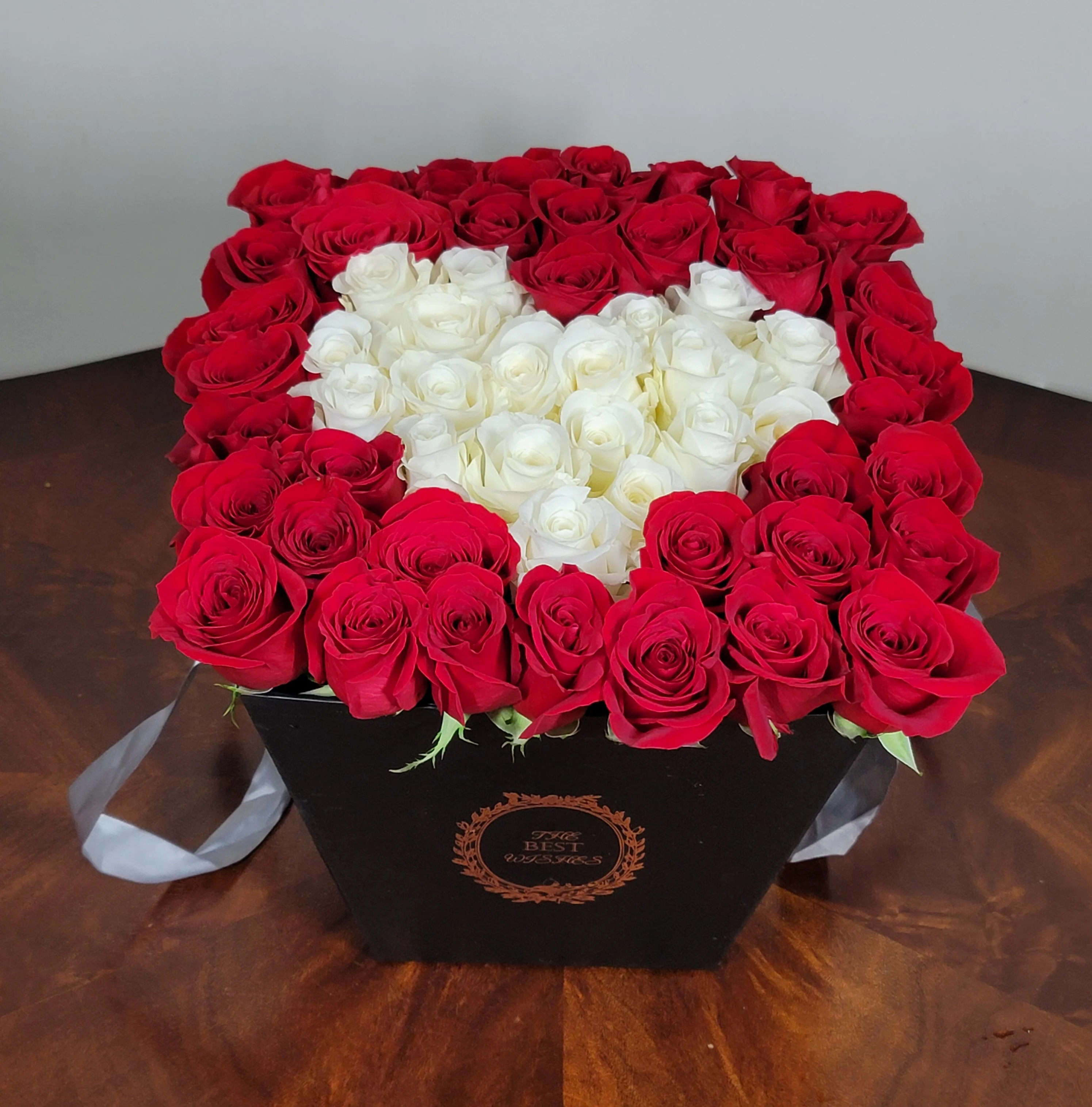 Heart-shaped box of red and white roses on a table