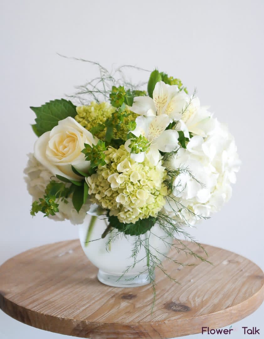 White and pale green floral arrangement in a glass vase