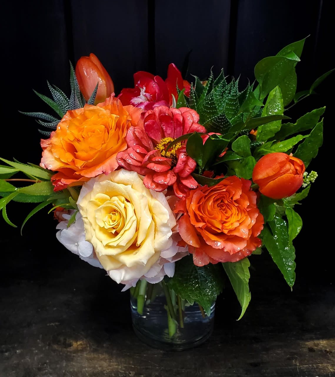 Colorful bouquet of roses and tulips in a clear glass vase