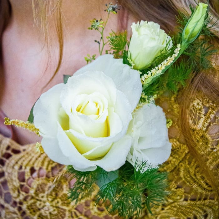 White rose corsage with green accents on a wrist